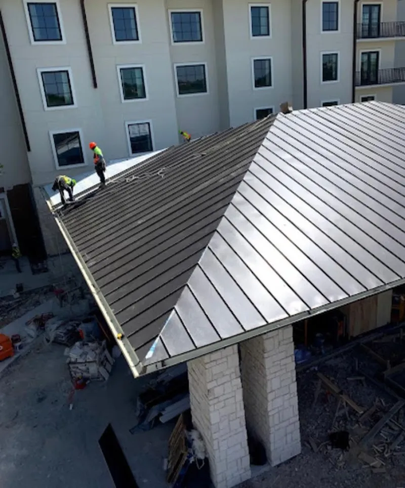Crew installing standing seam metal roof panels on a commercial project in Carol Stream